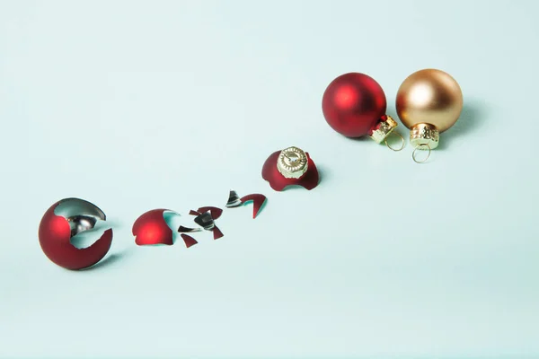 破碎的红色圣诞球和安全的两个在浅蓝色背景 选择玻璃球还是塑料球的概念 — 图库照片
