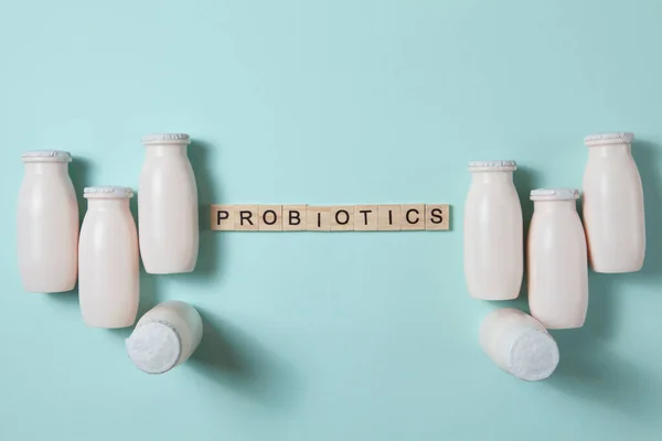 Bottles with probiotics and prebiotics dairy drink on light blue background. Bio yogurt with useful microorganisms. Production with biologically active additives. Fermentation and diet healthy food.