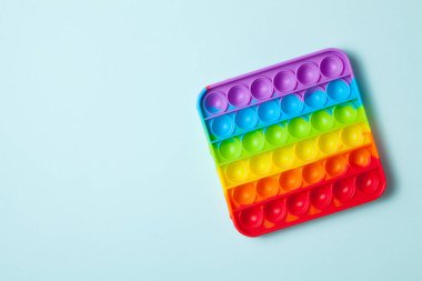 Gökkuşağı silikon duyusal antidepresan açık mavi arka planda oyuncak. Üst Manzara. Metin için boşluk.