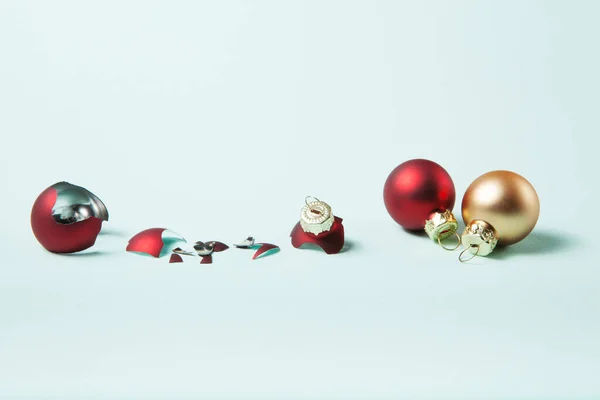 破碎的红色圣诞球和安全的两个在浅蓝色背景 选择玻璃球还是塑料球的概念 — 图库照片