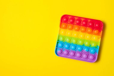 Gökkuşağı silikon duyusal antidepresan sarı arka planda oyuncak. Üst görünüm.