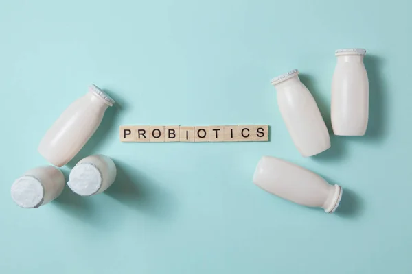 Bottles with probiotics and prebiotics dairy drink on light blue background.