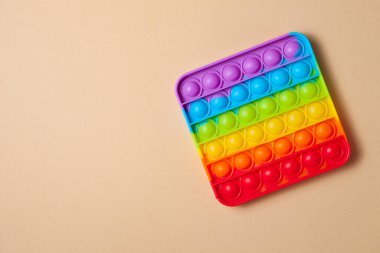 Gökkuşağı silikon duyusal antidepresan kahverengi arka planda oyuncak. Üst Manzara. Metin için boşluk.