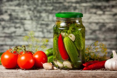 Ahşap arka planda turşu hazırlamak için cam kavanozlarda, baharatlarda ve sebzelerde salatalık turşusu..