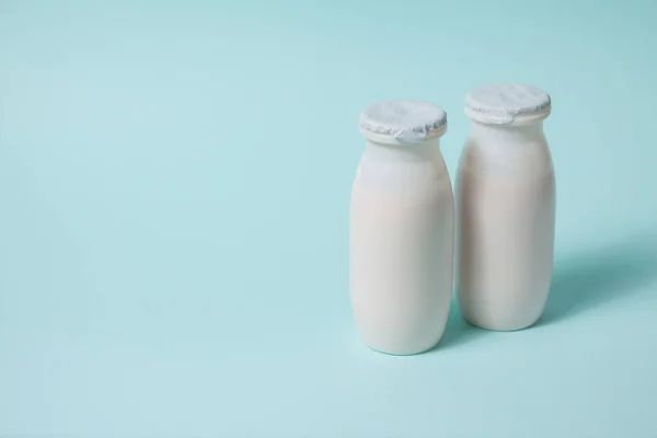 Botellas con probióticos y prebióticos bebida láctea sobre fondo azul claro. — Foto de Stock