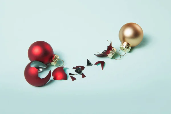 Kaputte rote Weihnachtskugel und sichere zwei Weihnachtskugeln auf hellblauem Hintergrund — Stockfoto