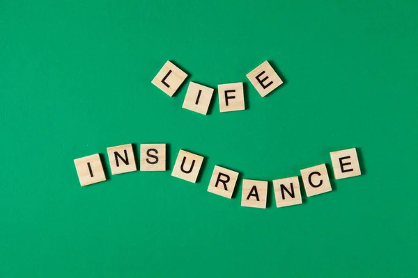 Slova životní pojištění podle dřevěných bloků na zeleném pozadí. — Stock fotografie