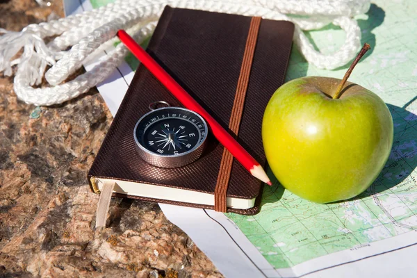 Notizbuch, Kompass, Apfel, Seil auf Steinhintergrund — Stockfoto