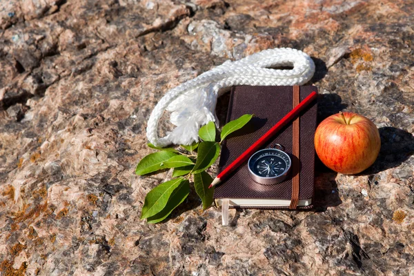 Quaderno, bussola, mela, corda su sfondo di pietra — Foto Stock