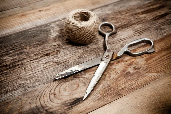 Tijeras viejas y yute de madeja sobre mesa de madera — Foto de Stock