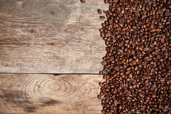 Kávová zrna na dřevěném stole — Stock fotografie