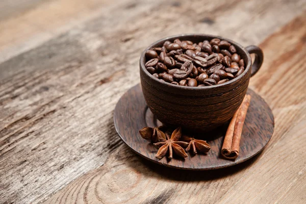 Kaffeetasse mit Kaffeebohnen auf Holztisch — Stockfoto