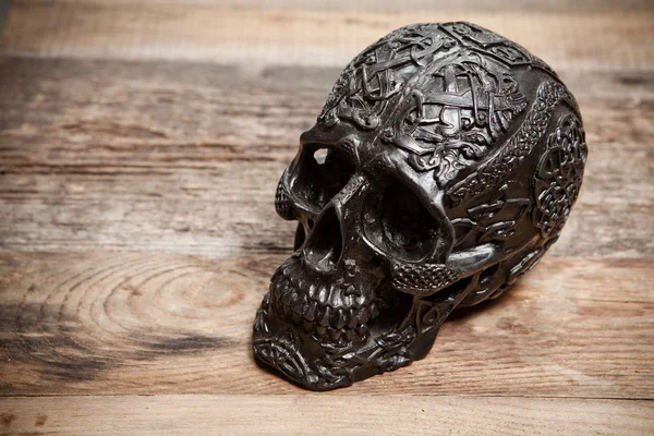 Calavera negra sobre mesa de madera — Foto de Stock