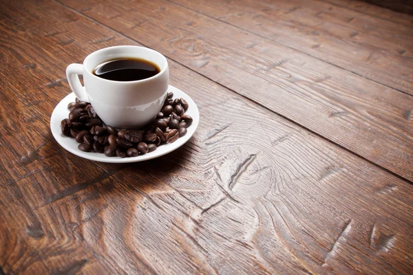 Filiżanka kawy i spodek na drewnianym stole — Zdjęcie stockowe