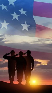 Gün batımı, gün doğumu ve Amerikan bayrağının arka planında selamlayan asker siluetleri. Gaziler Günü, Anma Günü, Bağımsızlık Günü. Sosyal medya ve hikayeler için yazıtlı dikey video.