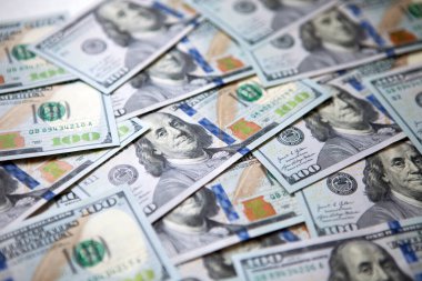 Arkaplandaki para yığını 100 Amerikan dolarının çoğunu karşılıyor. Üst görünüm.