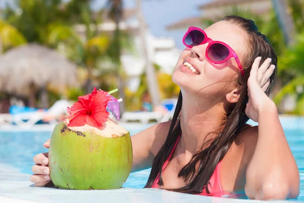 Vakker kvinne som drikker kokosnøtt ved bassenget – stockfoto