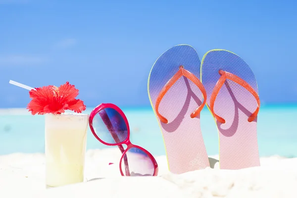 Färgstark bild flip flops, pina colada cocktail med hibiscus och rosa solglasögon nära stranden — Stockfoto