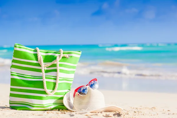 Bolsa de playa, gafas de sol y sombrero de paja en la playa tropical —  Fotos de Stock