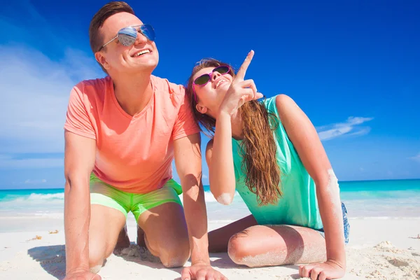 Par i ljusa kläder och hattar sitter på tropisk sandstrand — Stockfoto