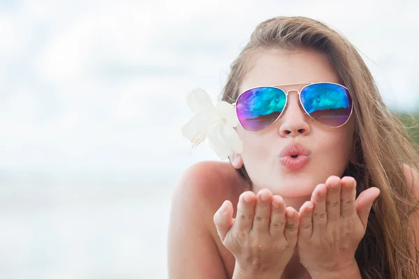 Portrait of a woman in sunglasses blowing a kiss at he beach — Stock Photo, Image