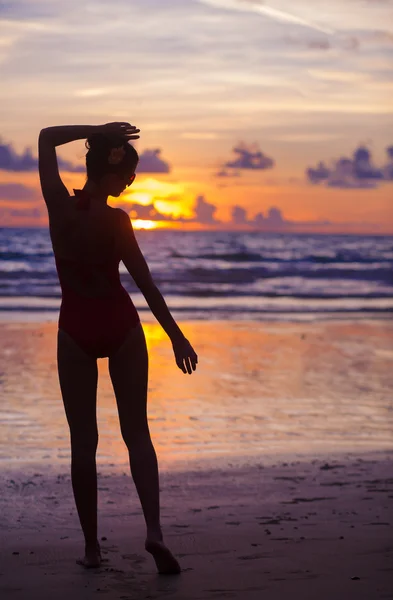 Silueta de puesta de sol de mujer en forma joven en la playa — Foto de Stock