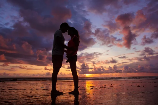 Sunset silhouette of young couple in love hugging at beach — Stock Photo, Image