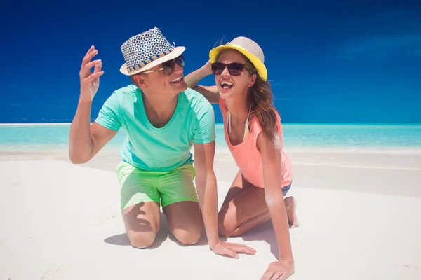 Pareja en ropa brillante y sombreros divirtiéndose en la playa tropical —  Fotos de Stock