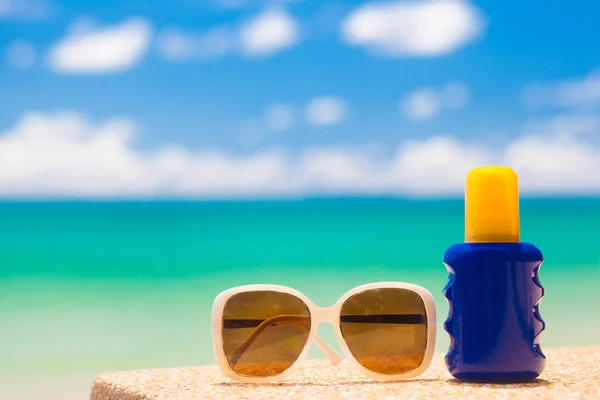 Zonnebrandcrème en zonnebril op tropisch strand — Stockfoto