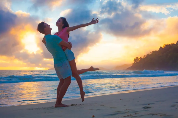 Pareja joven enamorada abrazándose en la playa al atardecer — Foto de Stock