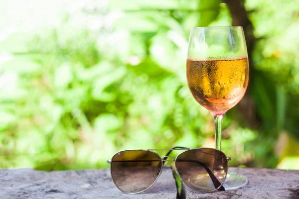 Bicchiere di vino rosato refrigerato sul tavolo su sfondo tropicale — Foto Stock