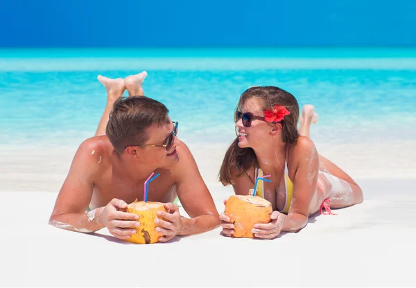 Feliz jovem casal deitado em uma praia tropical em Cayo Largo e beber um coquetel de coco — Fotografia de Stock