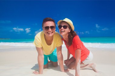 İki parlak kıyafetleri tropikal kumsalda eğleniyor sonra