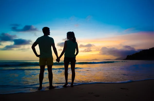 Silueta de puesta de sol de pareja joven enamorada en la playa — Foto de Stock