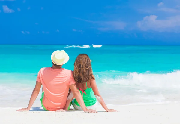 Vista trasera de pareja romántica en ropa brillante disfrutando de un día soleado en la playa tropical —  Fotos de Stock