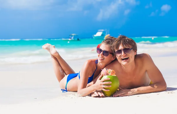 Retrato de jovem casal deitado em uma praia tropical em Barbados e bebendo um coquetel de coco — Fotografia de Stock