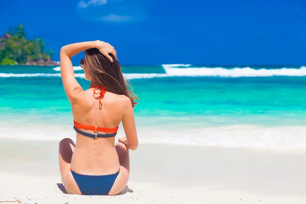 Vrouw in bikini zittend op het strand — Stockfoto