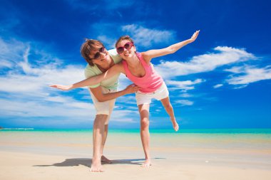 mutlu genç çift güneş gözlüğü parlak giysiler tropik sahilde eğleniyor