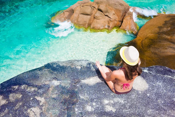 Belle femme aux cheveux longs en bikini relaxant sur les rochers au-dessus de la mer. Mahe Islan, Seychelles — Photo