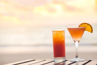 Margarita kokteyli ve aperol spreyi sahildeki masada. gün batımı arkaplanı