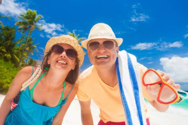 Kumsal aksesuarları olan mutlu genç çift sahilde eğleniyor.