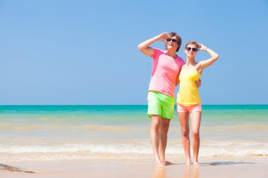 tropikal bir plaj gökyüzüne bakarak mutlu genç Çift