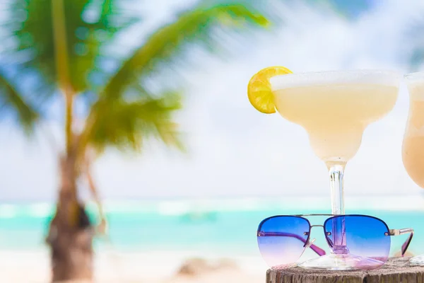 Foto de margarita fresca e óculos de sol na praia tropical — Fotografia de Stock
