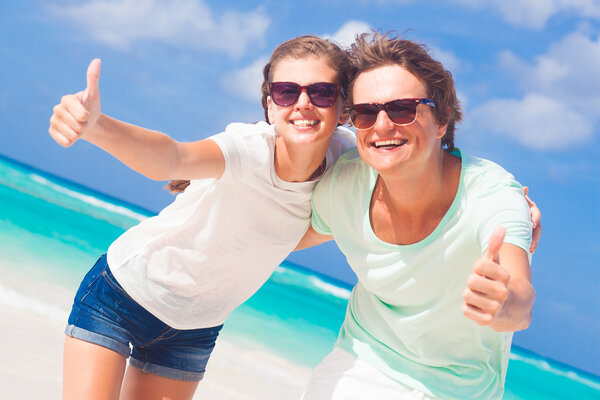 Closeup of happy young caucasian couple in sunglasses smiling on beach