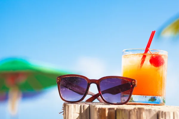 Cocktail de soco de rum e óculos de sol na praia tropical . — Fotografia de Stock