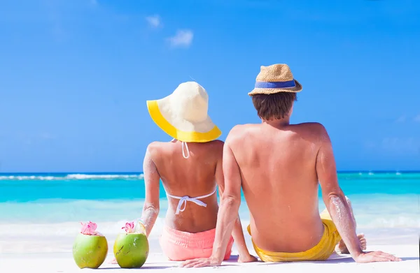 Vista traseira do casal sentado na praia tropical com dois coquetéis de coco frescos — Fotografia de Stock