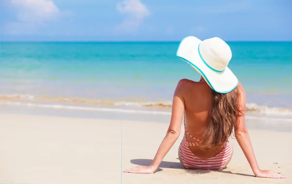 Ung kvinna i baddräkt och solglasögon liggande på stranden — Stockfoto