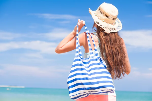 Back view of a fit young woman with stripy bag at tropical beach — Stock Photo, Image