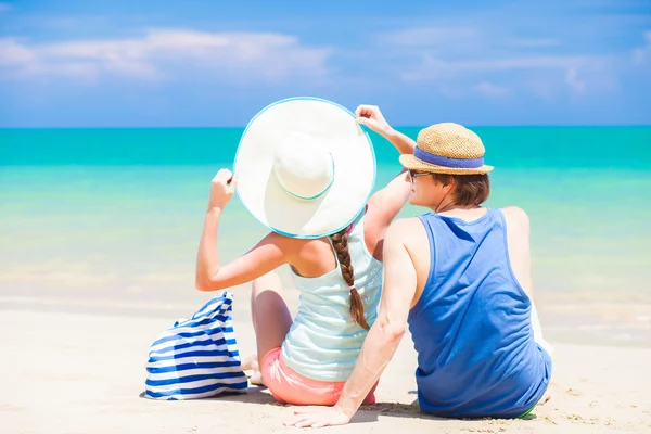 Vista trasera de pareja en sombreros de paja sentados en la playa tropical —  Fotos de Stock