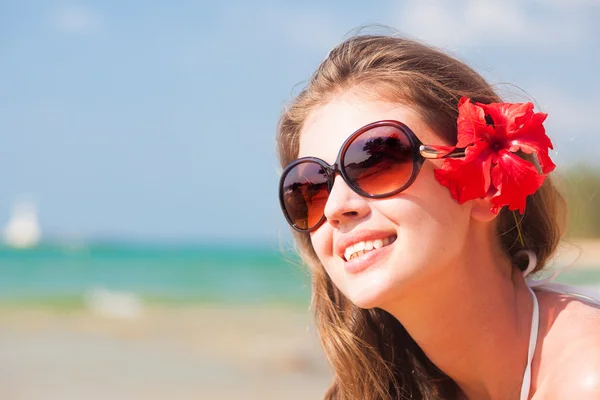 Closeup long haired woman in bikini with flower in hair on tropical beach — Stock Photo, Image